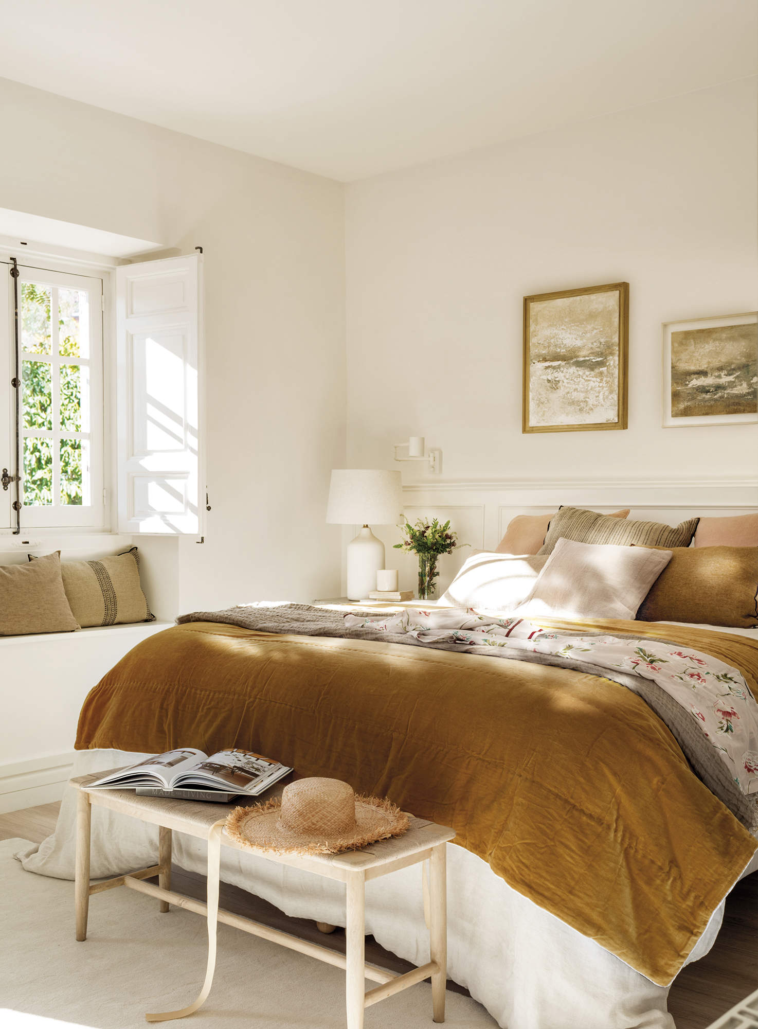 dormitorio con ropa de cama color mostaza, banco bajo ventana, banqueta de madera y fibra